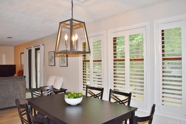 dining space with wood-type flooring and a textured ceiling