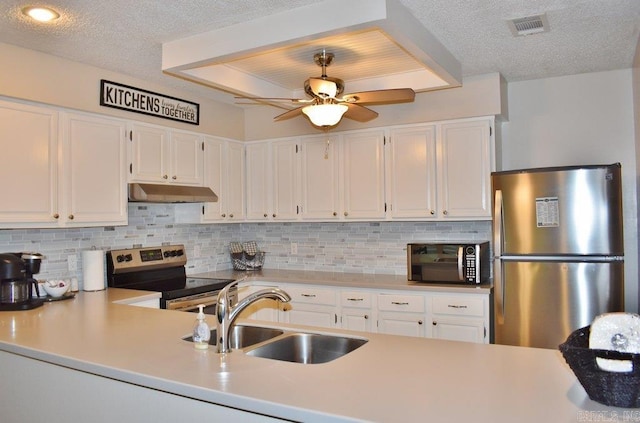 kitchen with stainless steel appliances, a raised ceiling, white cabinets, tasteful backsplash, and sink