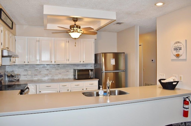 kitchen with wall chimney range hood, stainless steel appliances, sink, and white cabinetry