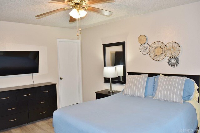 bedroom featuring ceiling fan, a textured ceiling, and light hardwood / wood-style floors