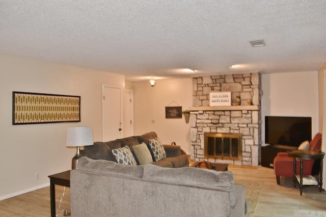 living room with wood-type flooring, a fireplace, and a textured ceiling