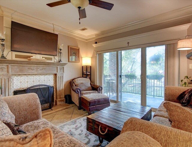 living room featuring ceiling fan, a healthy amount of sunlight, a tile fireplace, and light tile patterned floors