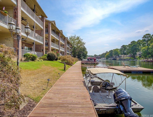 dock area with a balcony, a lawn, and a water view