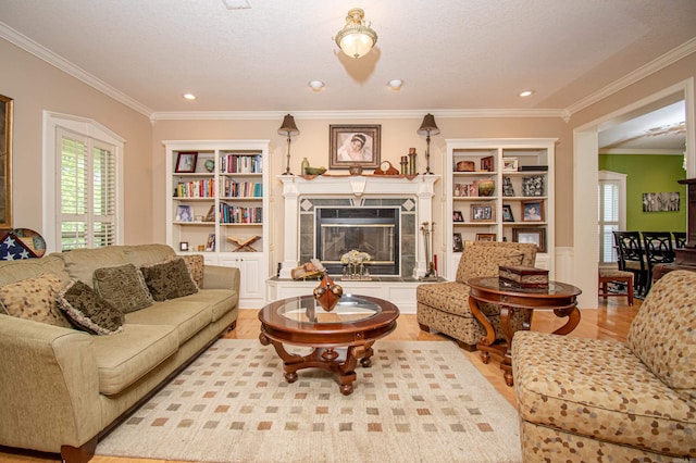 living room featuring a fireplace, built in shelves, ornamental molding, and light hardwood / wood-style floors