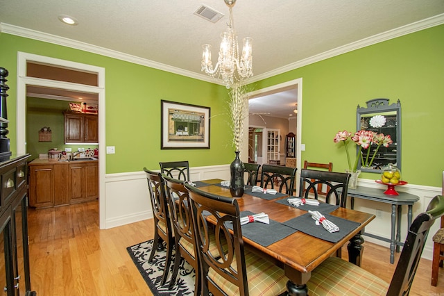 373 S Brandon, Fordyce, AR 71742 - dining space with an inviting chandelier, wainscoting, light wood-style floors, ornamental molding, and visible vents
