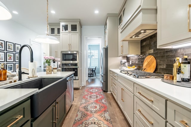 kitchen with premium range hood, appliances with stainless steel finishes, tasteful backsplash, white cabinetry, and hanging light fixtures