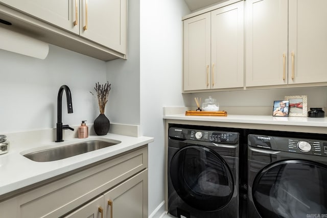 clothes washing area featuring cabinets, washing machine and clothes dryer, and sink