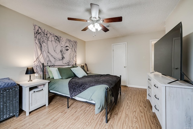 bedroom featuring ceiling fan, light hardwood / wood-style flooring, and a textured ceiling