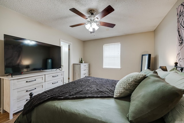 bedroom with ceiling fan, a textured ceiling, and hardwood / wood-style floors