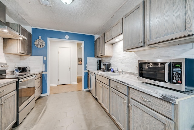 kitchen featuring appliances with stainless steel finishes, light hardwood / wood-style flooring, decorative backsplash, and wall chimney exhaust hood