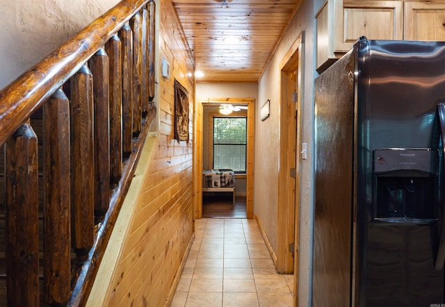 hall with light tile patterned flooring and wooden walls