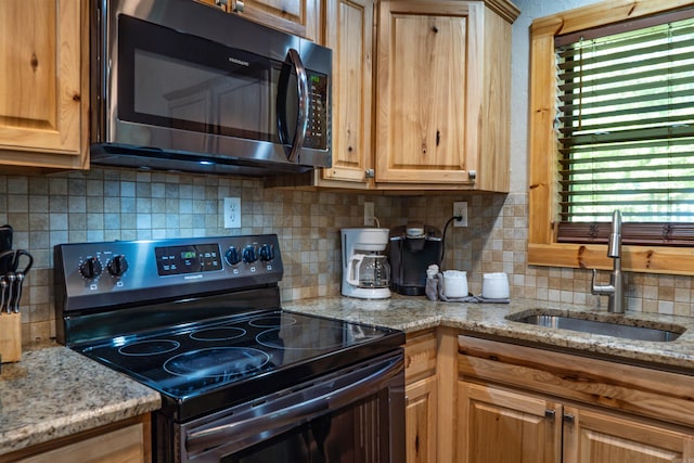 kitchen featuring sink, light stone counters, electric range, and decorative backsplash