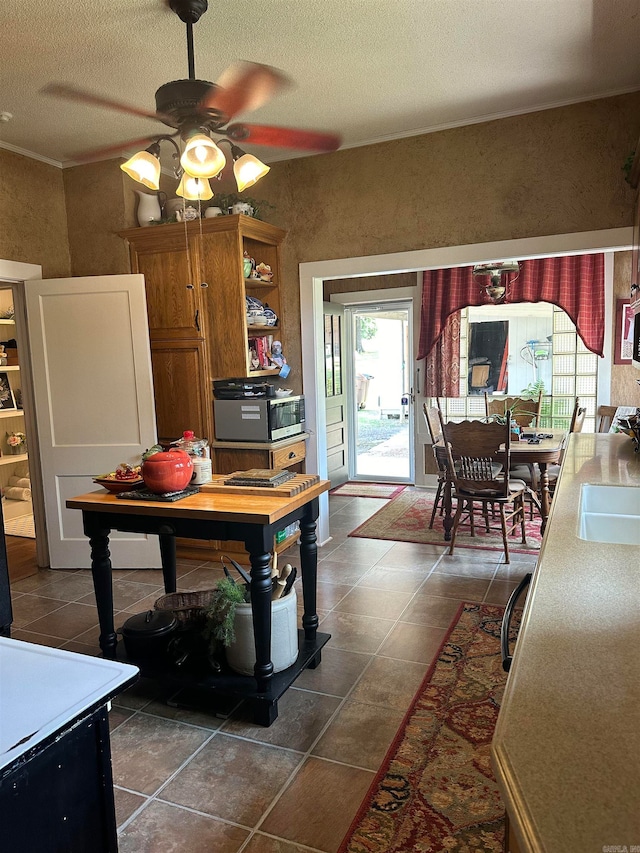 kitchen with ceiling fan, a textured ceiling, and dark tile patterned floors