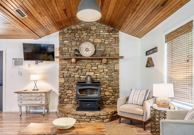 living room featuring vaulted ceiling, a wall mounted AC, hardwood / wood-style flooring, and a wood stove