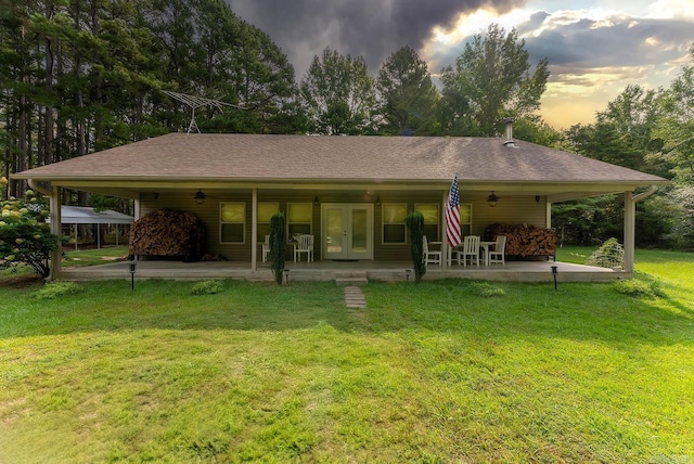 back house at dusk with a patio and a yard