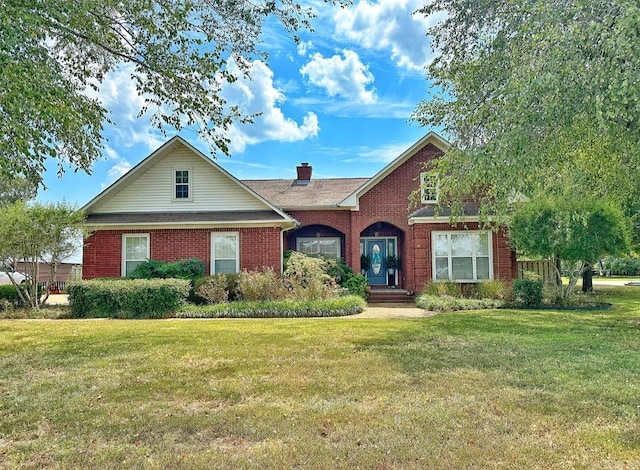 view of front of property featuring a front yard, a chimney, and brick siding