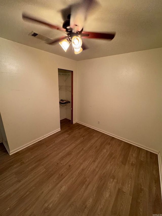 unfurnished bedroom featuring dark hardwood / wood-style flooring, a closet, a textured ceiling, and ceiling fan