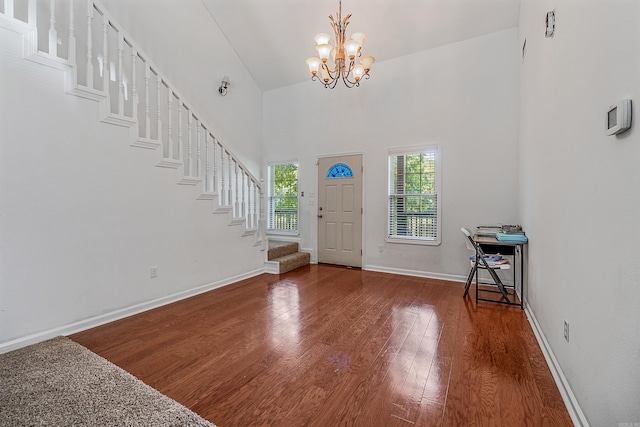 foyer featuring hardwood / wood-style floors, a towering ceiling, and a notable chandelier