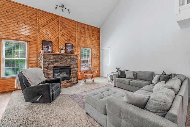 living room featuring a fireplace, wooden walls, high vaulted ceiling, and rail lighting