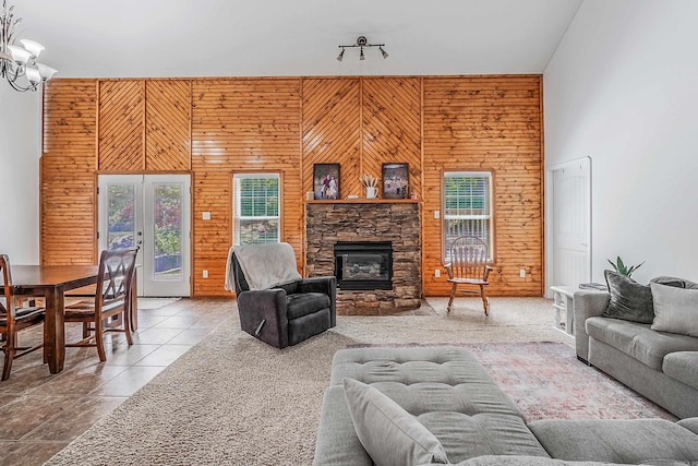 tiled living room featuring a wealth of natural light, a fireplace, wood walls, and a high ceiling