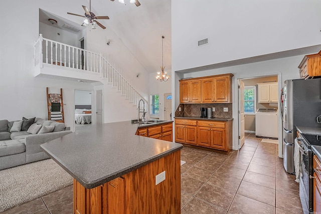 kitchen featuring high vaulted ceiling, tasteful backsplash, ceiling fan with notable chandelier, appliances with stainless steel finishes, and washer / clothes dryer