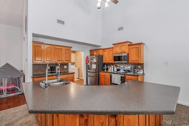 kitchen featuring sink, a high ceiling, appliances with stainless steel finishes, tasteful backsplash, and ceiling fan