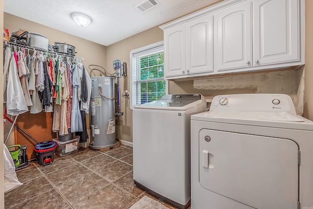 laundry room with gas water heater, cabinets, washer and clothes dryer, dark tile patterned flooring, and a textured ceiling