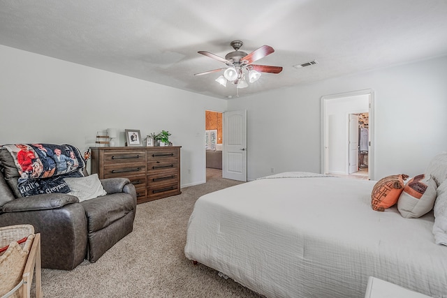 bedroom with ceiling fan, light colored carpet, and ensuite bathroom