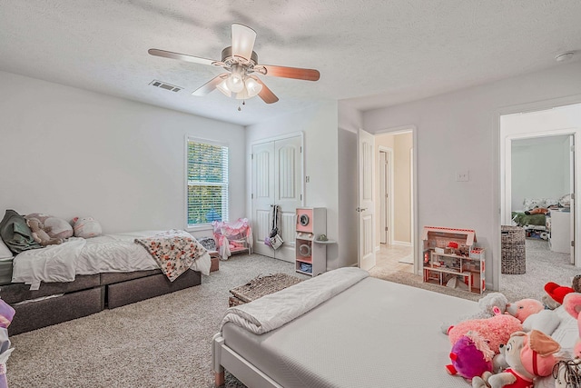 carpeted bedroom with ceiling fan, a closet, and a textured ceiling