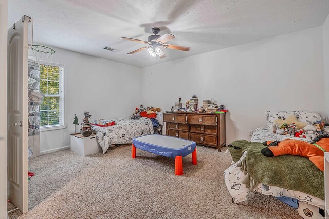 bedroom featuring a textured ceiling, ceiling fan, and light carpet