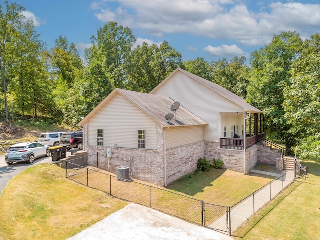 view of side of home featuring central AC unit, a porch, and a lawn