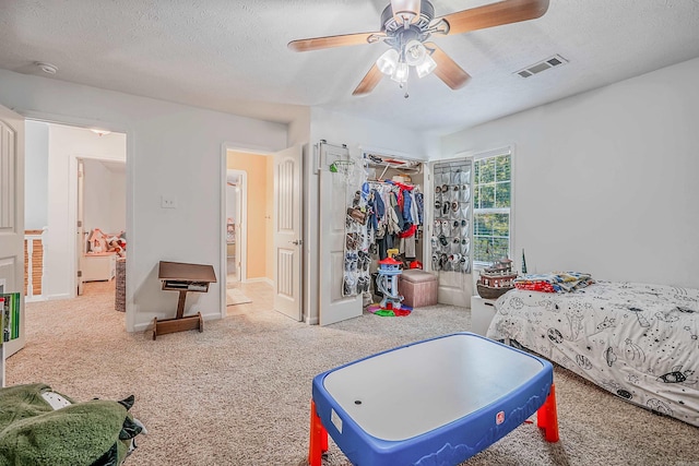 carpeted bedroom featuring ceiling fan, a closet, and a textured ceiling