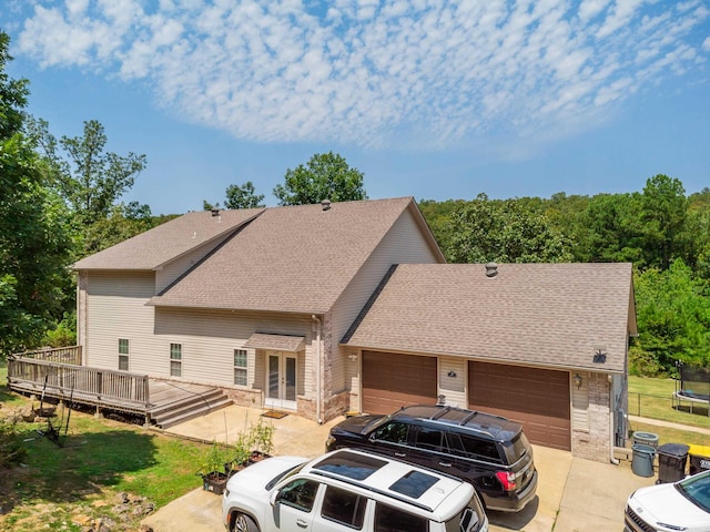 view of front facade with a garage, a trampoline, and a deck