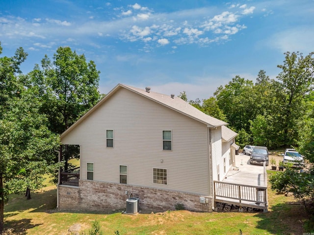 view of home's exterior featuring a garage, central AC unit, a deck, and a yard