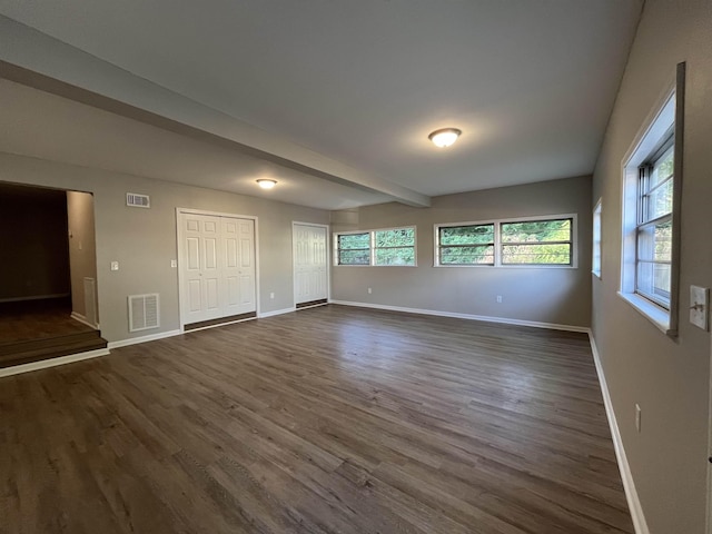 unfurnished room with dark hardwood / wood-style floors and beam ceiling