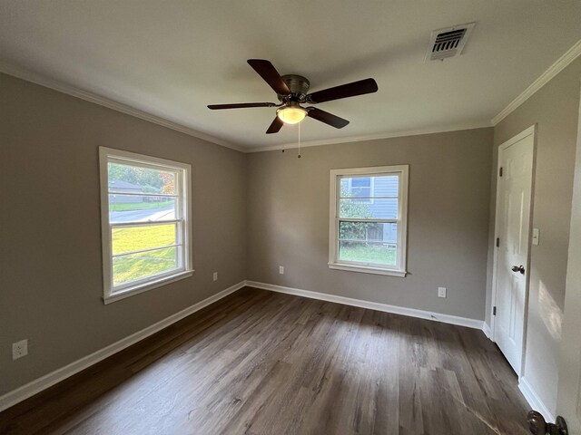 spare room featuring dark hardwood / wood-style flooring, ceiling fan, crown molding, and a healthy amount of sunlight