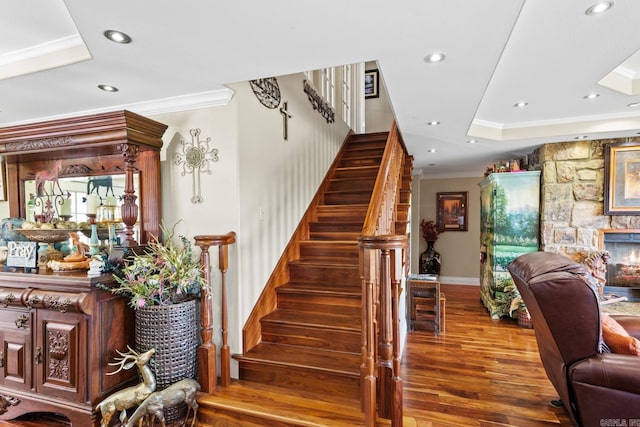 stairway featuring ornamental molding, recessed lighting, a fireplace, and wood finished floors