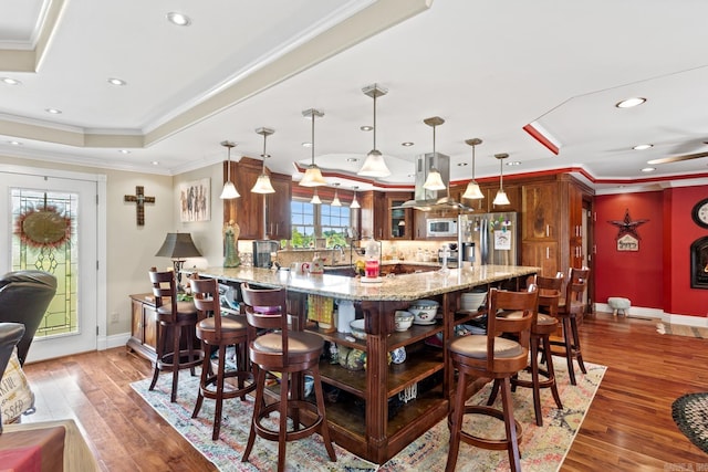 kitchen with crown molding, stainless steel refrigerator with ice dispenser, a peninsula, and white microwave