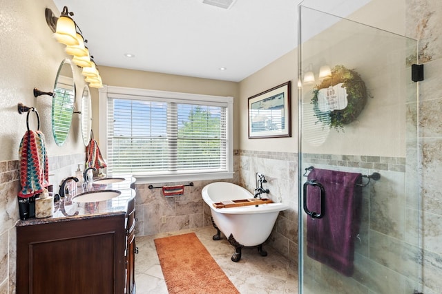 full bath with a stall shower, tile patterned flooring, a freestanding bath, vanity, and tile walls