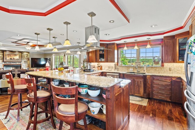 kitchen featuring plenty of natural light, a tray ceiling, island exhaust hood, and a fireplace