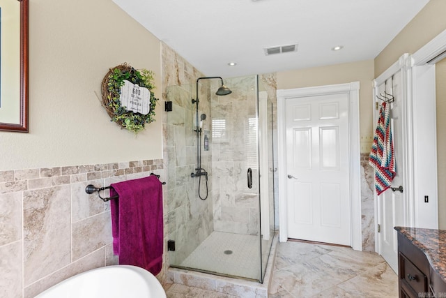 bathroom with tile walls, a soaking tub, visible vents, a stall shower, and vanity