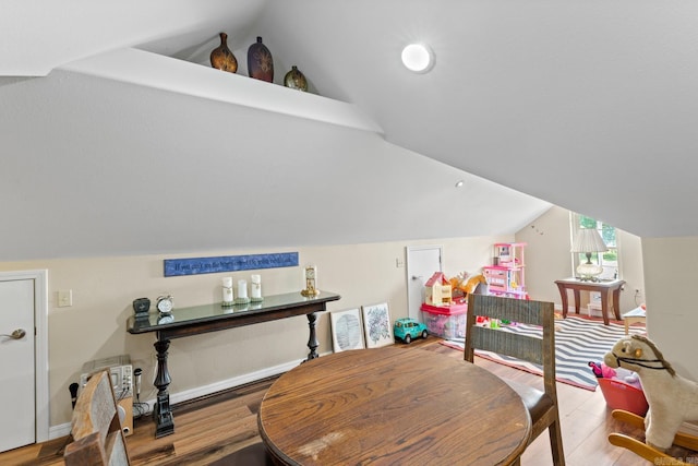 dining space featuring lofted ceiling, baseboards, and wood finished floors