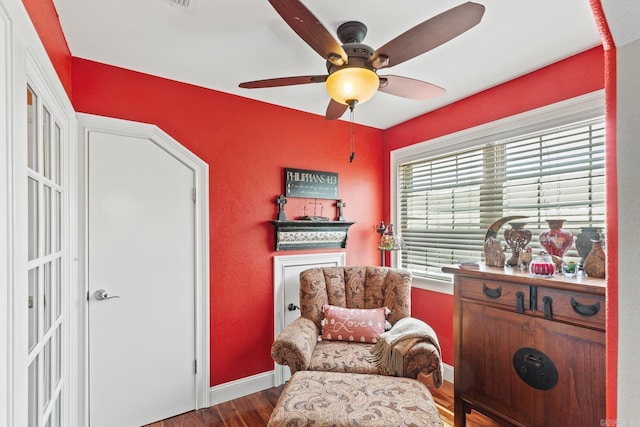 living area featuring a ceiling fan, baseboards, and wood finished floors