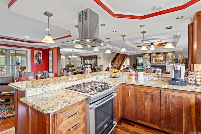 kitchen with open floor plan, gas stove, a raised ceiling, and island range hood