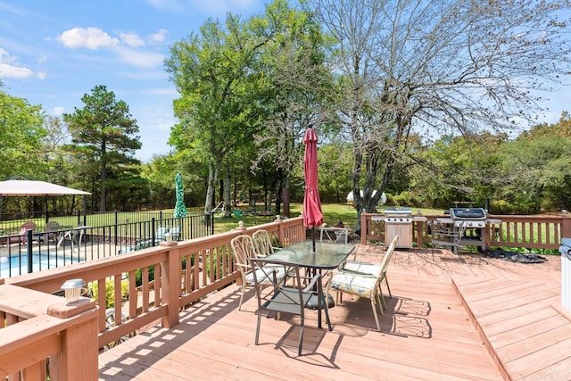 wooden deck with outdoor dining area, area for grilling, fence, and a fenced in pool