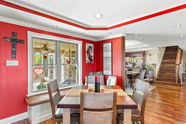 dining area featuring crown molding, stairs, a raised ceiling, and wood finished floors