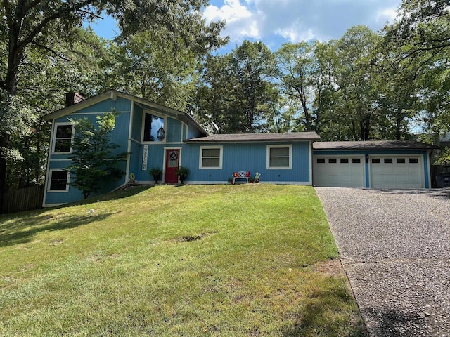 tri-level home with driveway, an attached garage, a chimney, and a front lawn