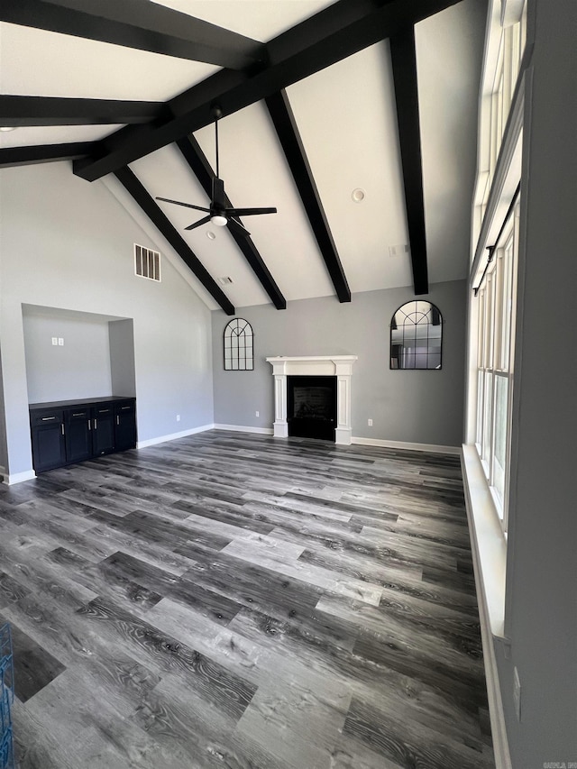 unfurnished living room with ceiling fan, high vaulted ceiling, and beam ceiling