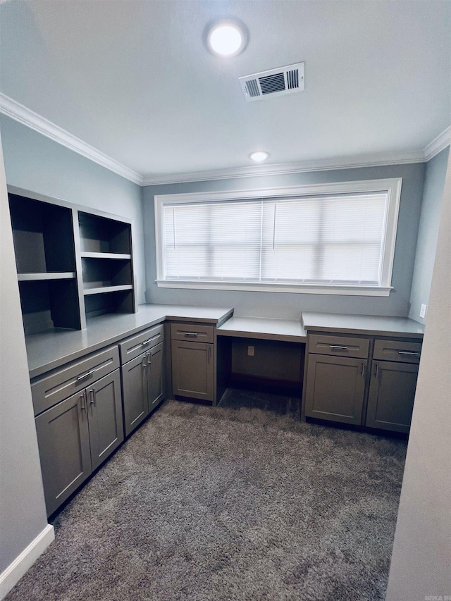 kitchen with dark colored carpet, built in desk, and ornamental molding