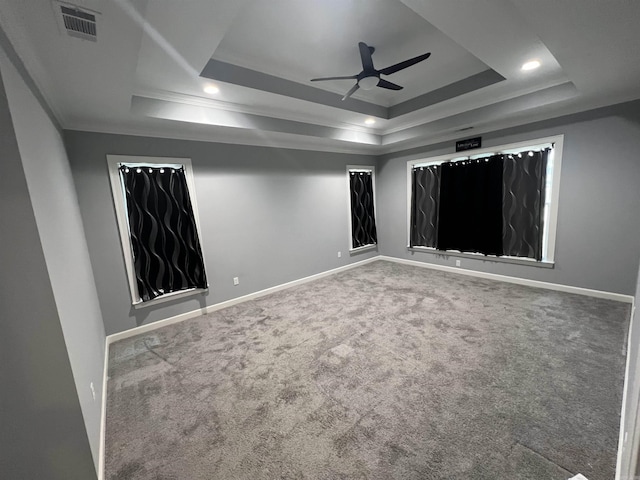 carpeted spare room featuring ceiling fan and a tray ceiling